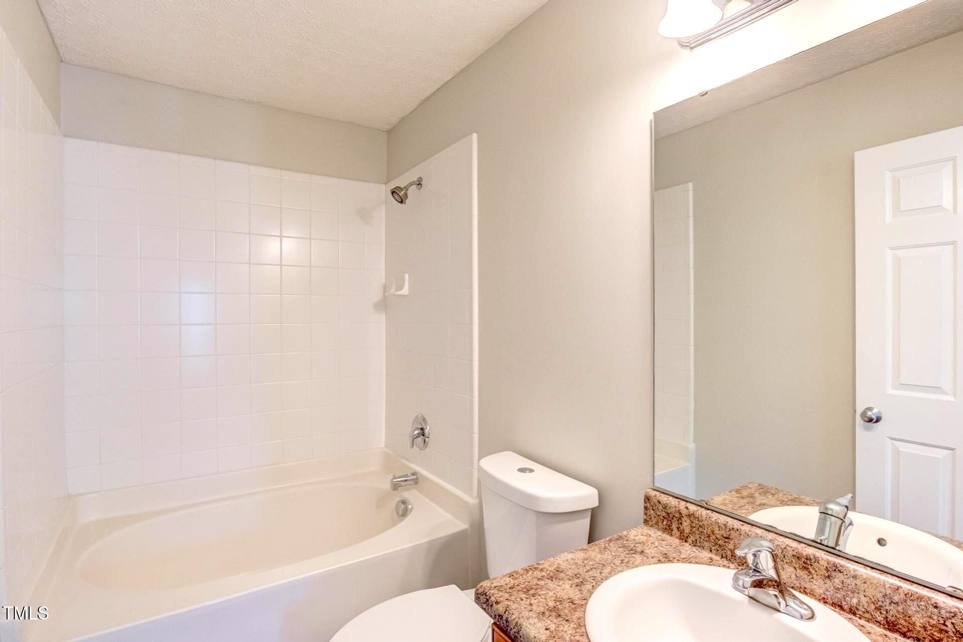 4 Intrepid Court Durham, NC 27703 - Photo 14 of 25 a bathroom with a granite countertop toilet a sink and a bathtub