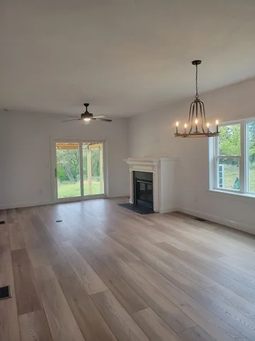 an empty room with wooden floor fireplace and windows