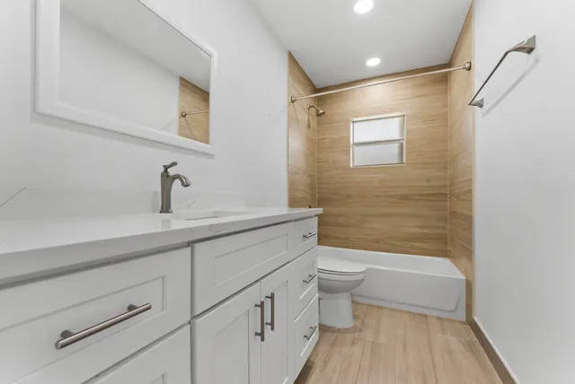 a bathroom with a bathtub shower sink vanity and toilet