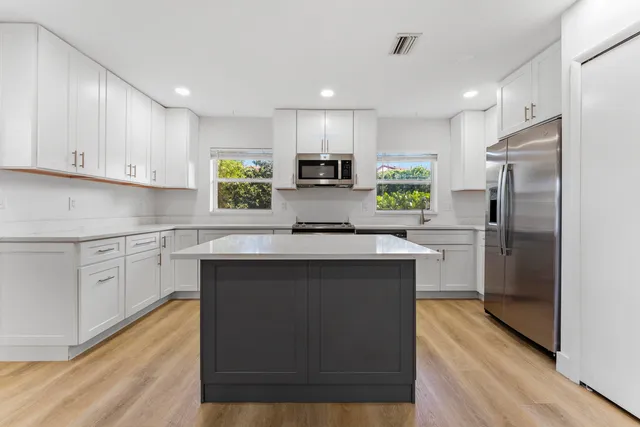 a kitchen with kitchen island white cabinets and stainless steel appliances