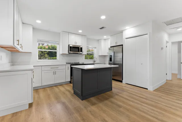 a kitchen with a refrigerator cabinets and wooden floor