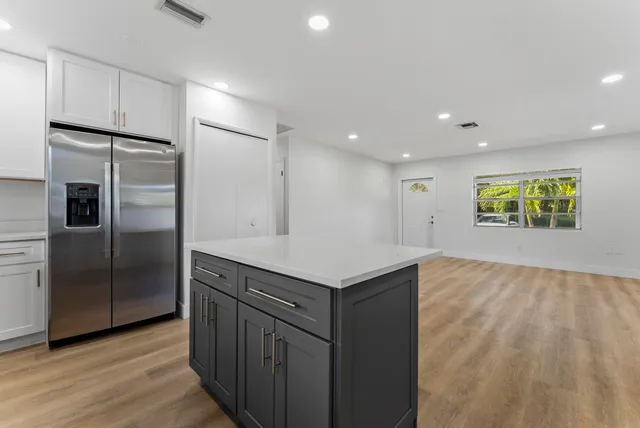 a kitchen with kitchen island a counter top space wooden floor and stainless steel appliances