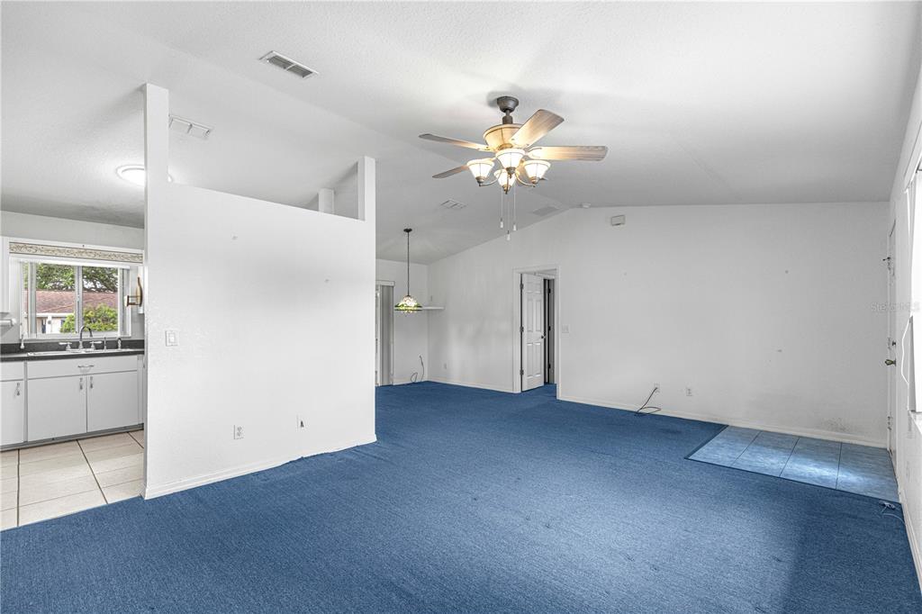 9840 Southwest 63rd Court Ocala, FL 34476 - Photo 21 of 49 an empty room with a chandelier fan and wooden floor