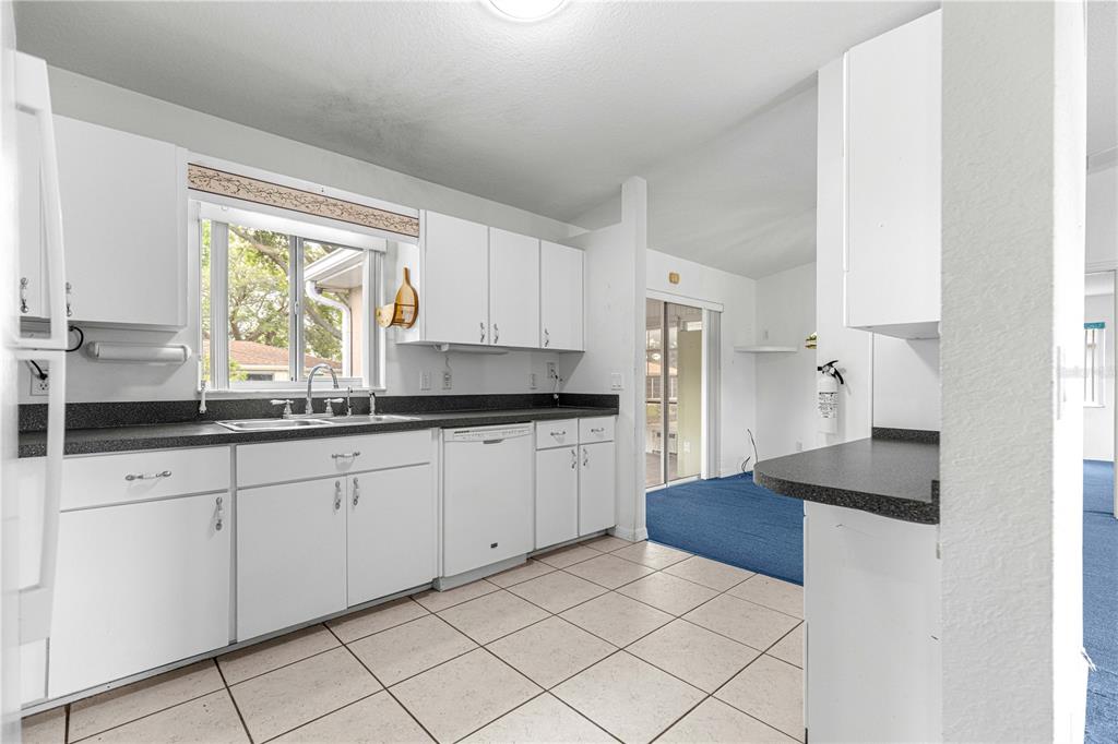 9840 Southwest 63rd Court Ocala, FL 34476 - Photo 23 of 49 a kitchen with granite countertop white cabinets white appliances a sink and a large window