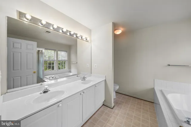 a spacious bathroom with a double vanity sink a large mirror and a bathtub