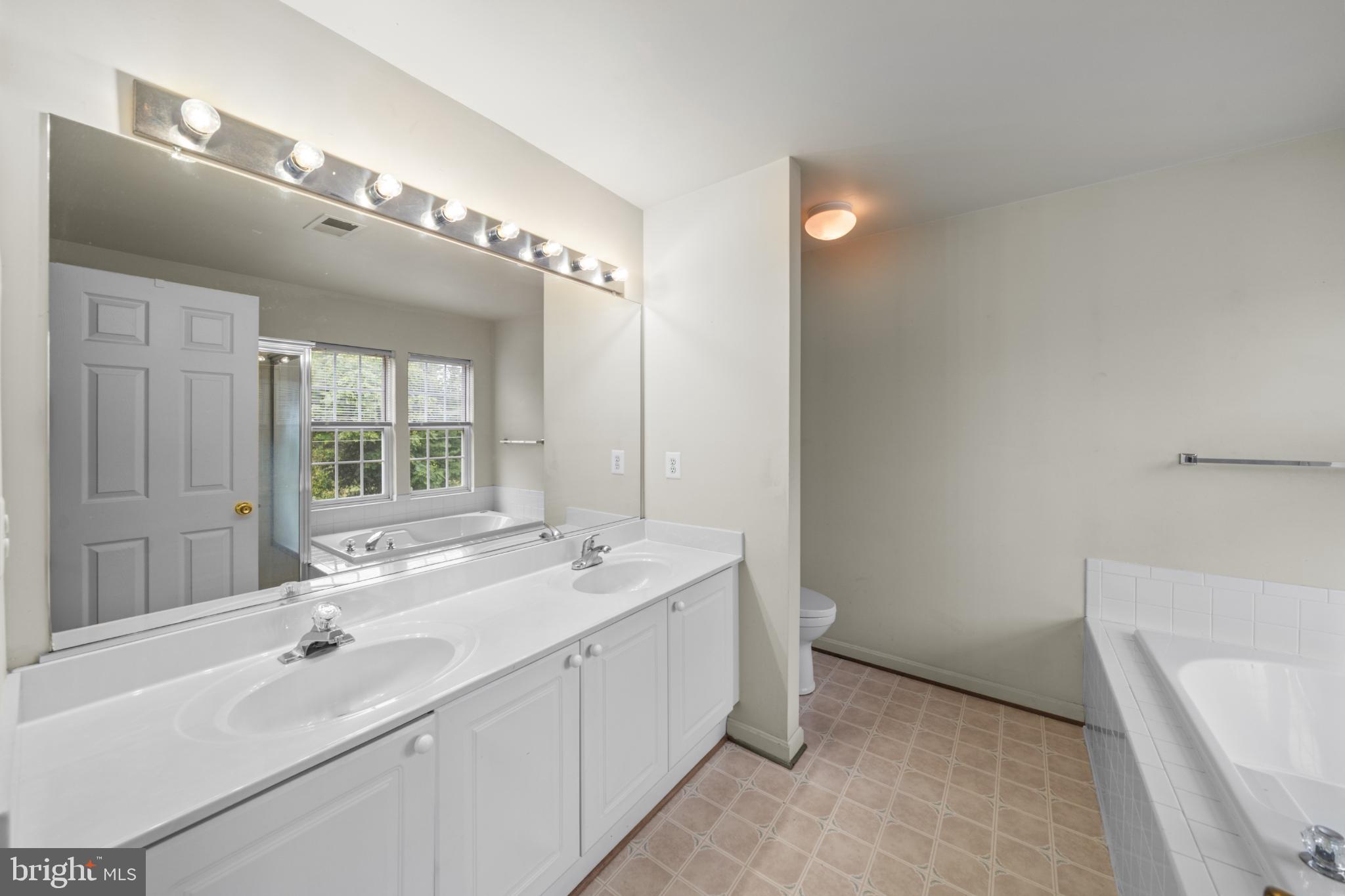 15381 Tina Lane Woodbridge, VA 22193 - Photo 23 of 32 a spacious bathroom with a double vanity sink a large mirror and a bathtub
