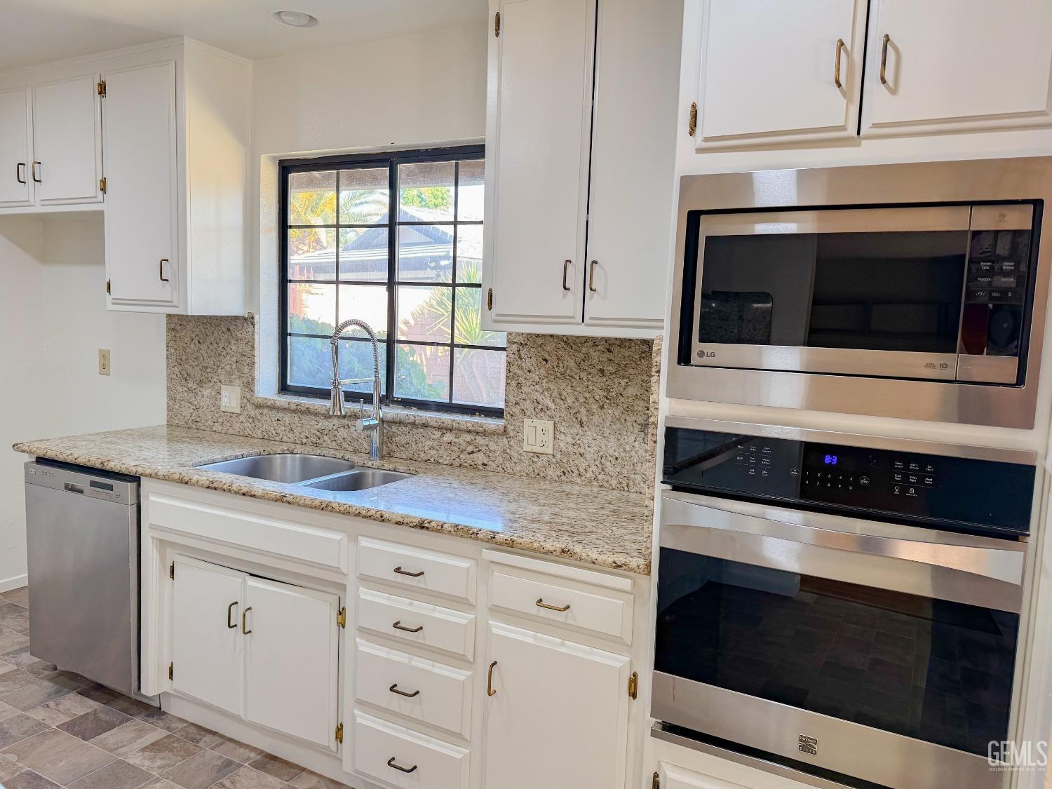 Undisclosed Address Bakersfield, CA 93307 - Photo 12 of 46 a kitchen with granite countertop white cabinets stainless steel appliances and sink
