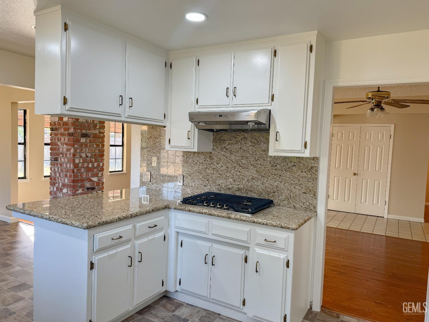 Undisclosed Address Bakersfield, CA 93307 - Photo 14 of 46 a kitchen with granite countertop white cabinets white appliances and granite countertops with wooden floor