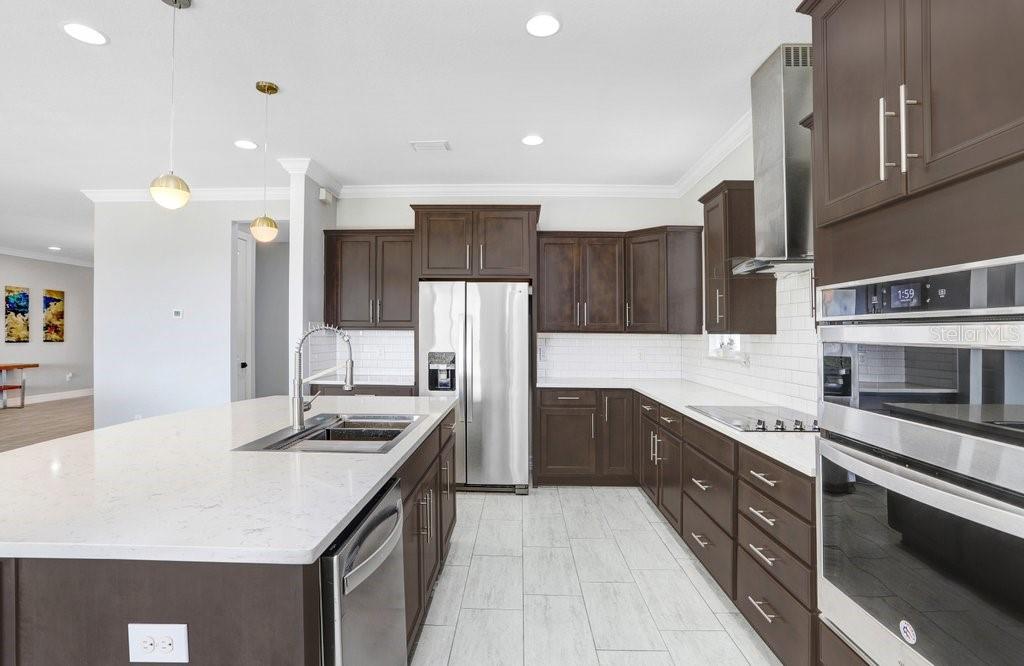 11677 Brighton Knoll Loop Riverview, FL 33579 - Photo 23 of 30 a kitchen with stainless steel appliances kitchen island granite countertop a kitchen island a stove a refrigerator a sink and dishwasher with wooden floor