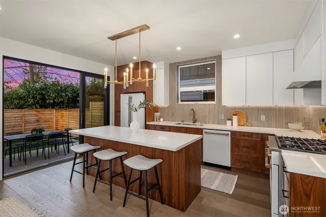 a kitchen with stainless steel appliances granite countertop a stove top oven a sink dishwasher a dining table and chairs with wooden floor