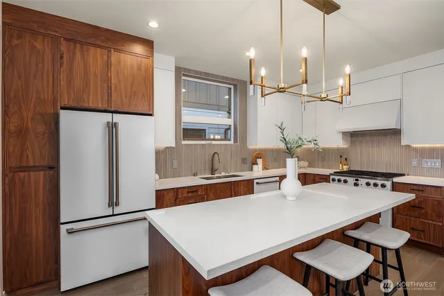 a kitchen with stainless steel appliances granite countertop a refrigerator a sink dishwasher a stove with white cabinets and wooden floor