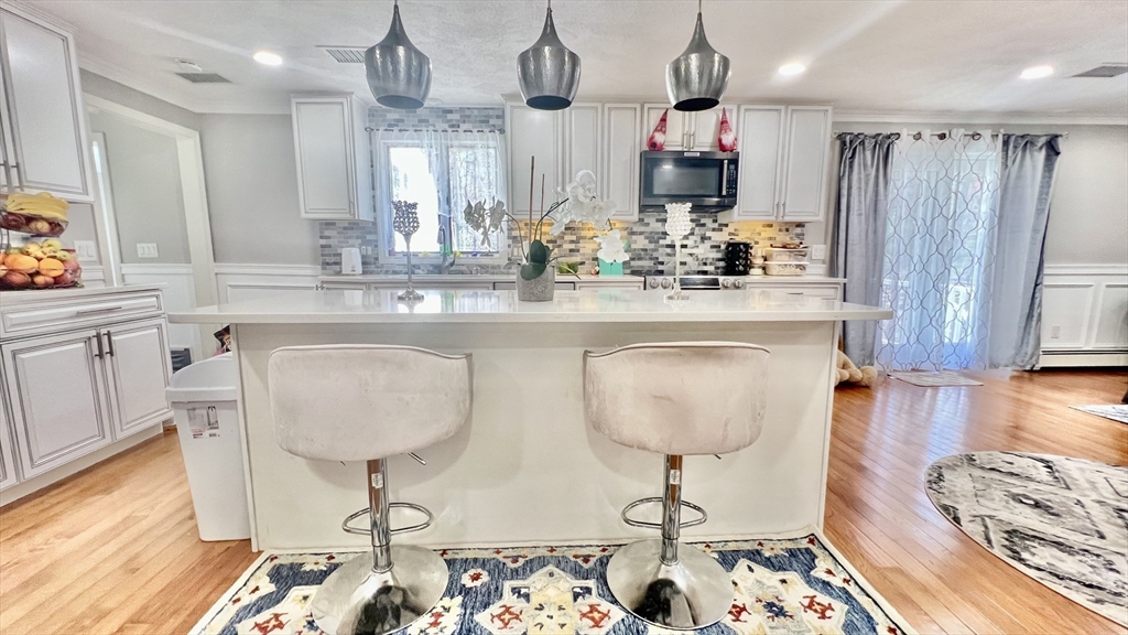 5 Flintlocke Road Franklin, MA 02038 - Photo 6 of 34 a spacious kitchen with stainless steel appliances granite countertop a sink a stove a dining table and chairs with wooden floor