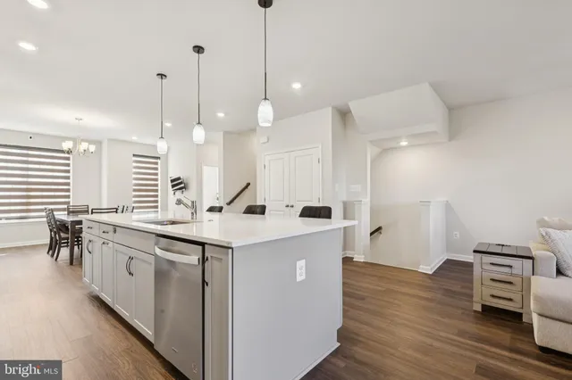 a kitchen with kitchen island a white counter top space a sink stainless steel appliances and cabinets