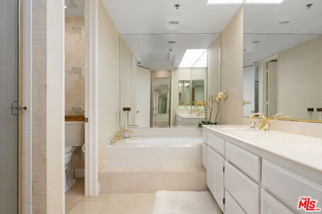 a bathroom with a double vanity sink mirror and bathtub
