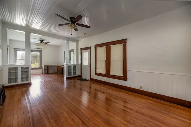 a view of an empty room with wooden floor and a window