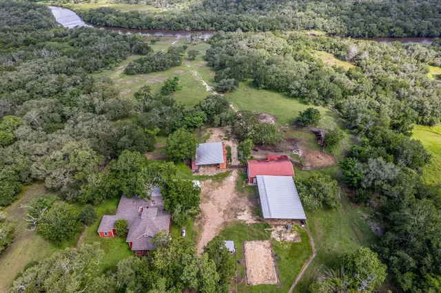 an aerial view of residential house with outdoor space and trees all around