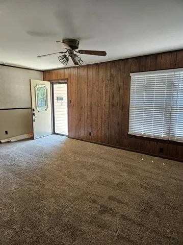 an empty room with windows and fan
