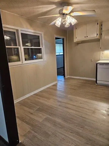 a view of empty room with wooden floor and kitchen view