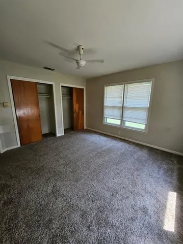 an empty room with windows and ceiling fan