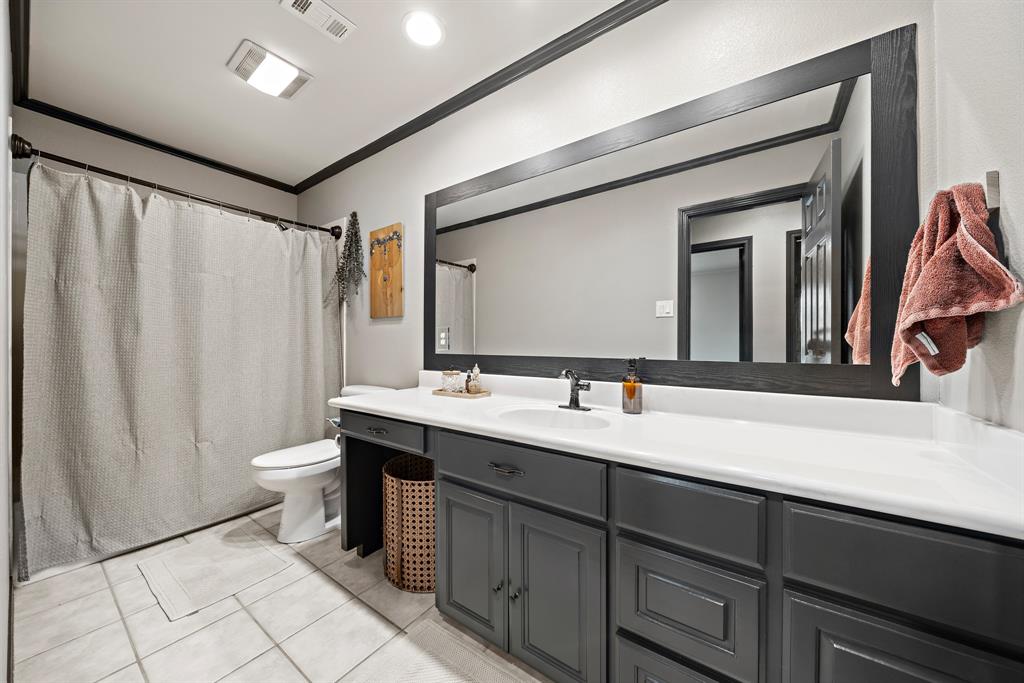 10512 Whitney Trace Drive Waco, TX 76708 - Photo 34 of 39 Bathroom featuring a dual vanity with dark cabinetry, white countertops, and a full-width framed mirror
