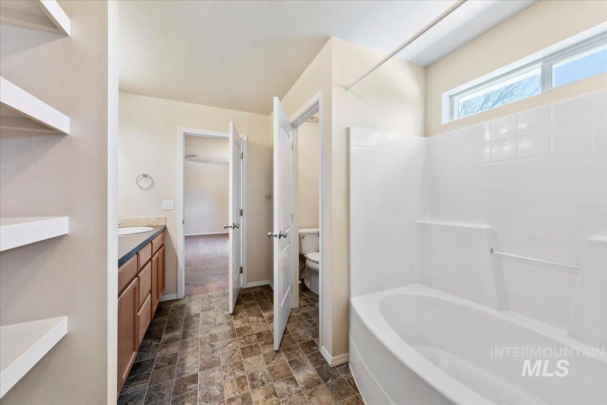 1555 Condor Drive Middleton, ID 83644 - Photo 26 of 50 Full bathroom featuring a built-in tub and shower combination with white tile surround, a single vanity with wood-finish cabinetry, and patterned floor tiling