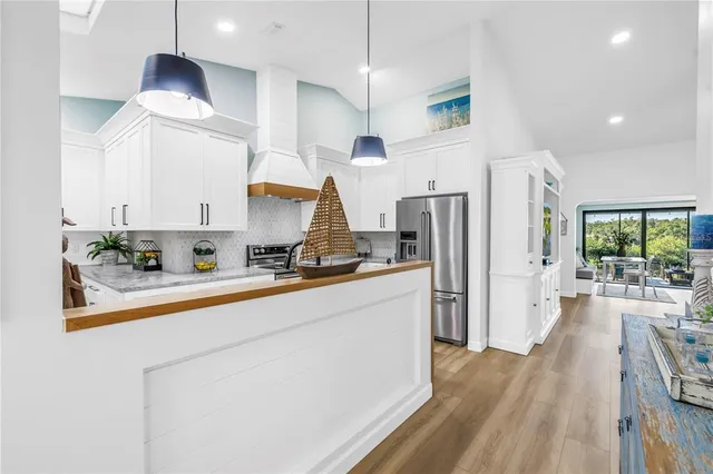 a kitchen with stainless steel appliances a refrigerator a stove a sink dishwasher and a dining table with wooden floor