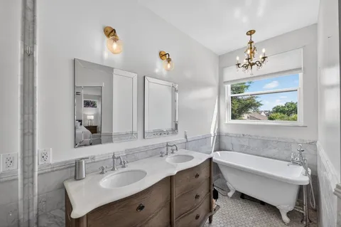 a bathroom with a tub double vanity sink and a large mirror