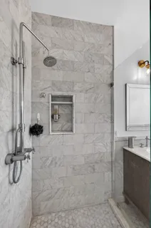 a bathroom with a granite countertop shower a mirror and vanity