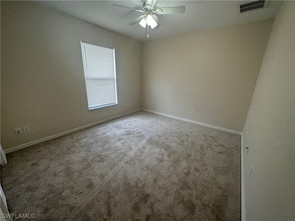 12956 Stone Tower Loop Fort Myers, FL 33913 - Photo 19 of 26 an empty room with a chandelier fan and windows