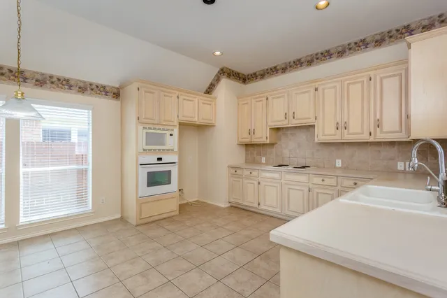 a kitchen with granite countertop white cabinets white appliances with a sink and dishwasher