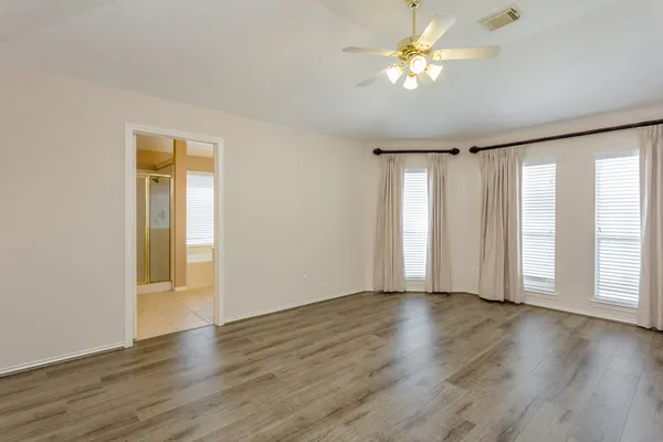 a view of an empty room with a window and wooden floor