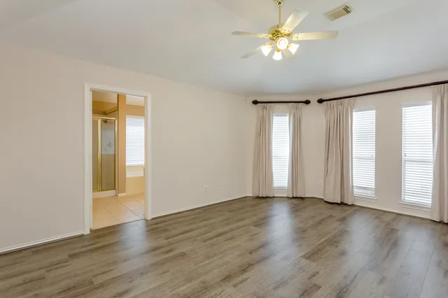 a view of an empty room with a window and wooden floor