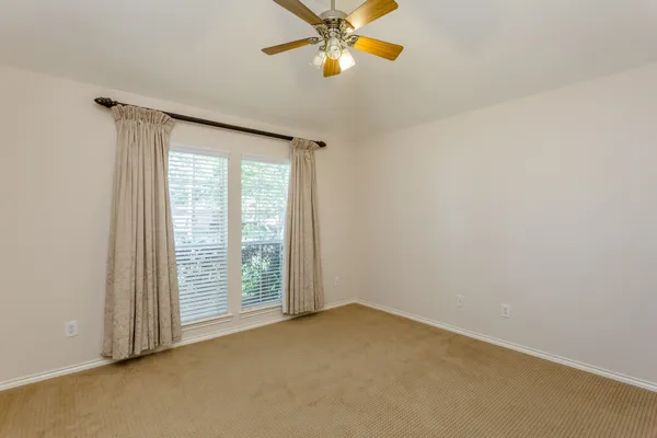an empty room with a window and chandelier fan