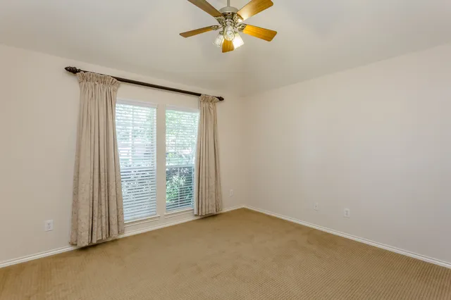 an empty room with a window and chandelier fan