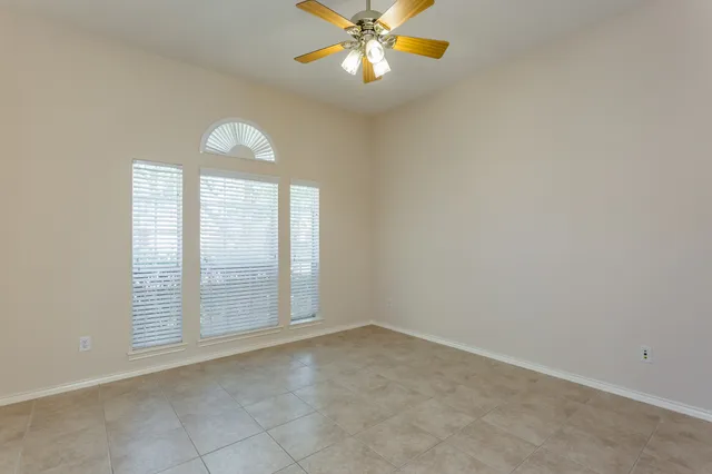 an empty room with windows and ceiling fan