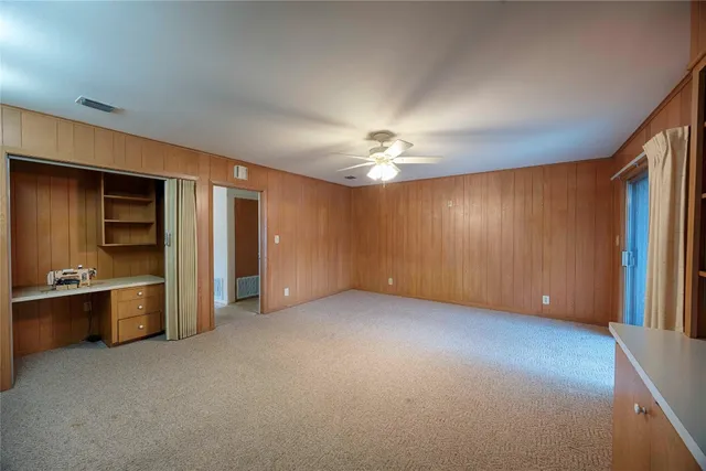 an empty room with chandelier fan and windows
