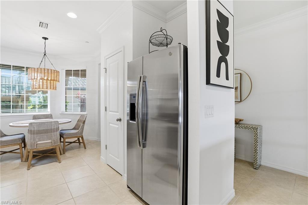 9374 Pocida Court, Unit 101 Naples, FL 34119 - Photo 11 of 32 a kitchen with refrigerator a table and chairs
