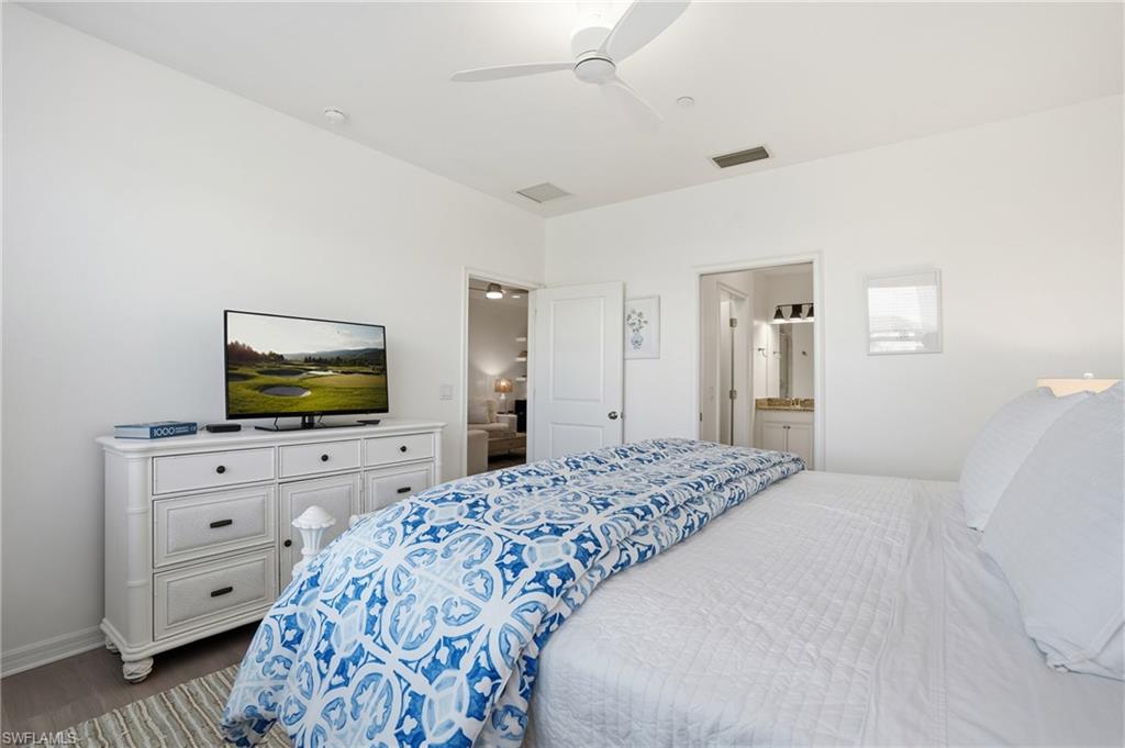 9374 Pocida Court, Unit 101 Naples, FL 34119 - Photo 19 of 32 a bedroom with a bed and flat screen tv