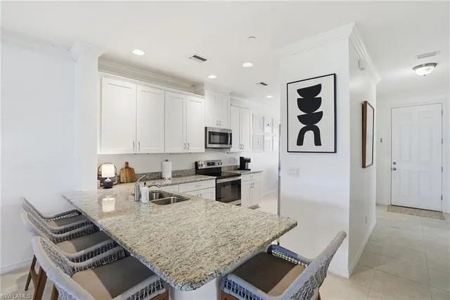 a kitchen with stainless steel appliances kitchen island granite countertop a stove and white cabinets