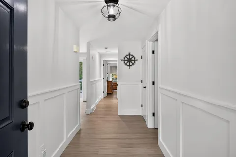 a view of a hallway with wooden floor and chandelier