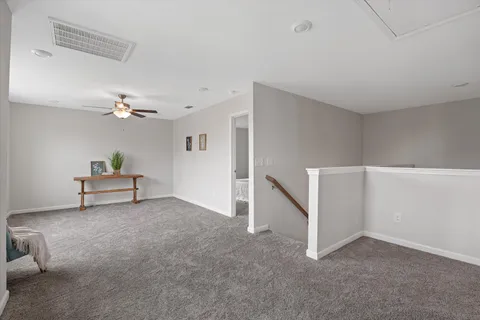a view of empty room with stairs and fan