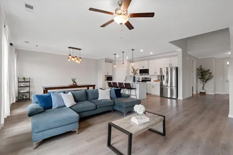 a living room with furniture kitchen view and a chandelier
