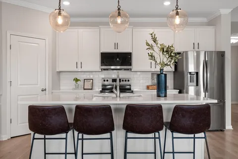 a kitchen with stainless steel appliances a stove a refrigerator and a dining table with white cabinets