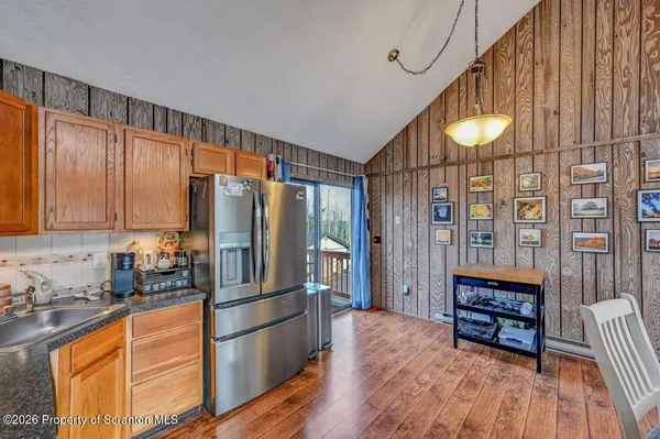 a kitchen with granite countertop a refrigerator a stove a sink and a dining table with wooden floor