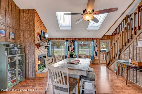 a dining room with wooden floor a chandelier a wooden table and chairs