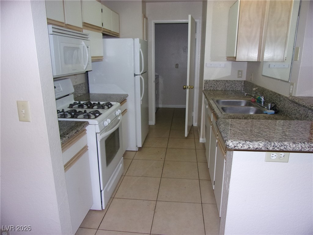 2200 South Fort Apache Road, Unit 2178 Las Vegas, NV 89117 - Photo 3 of 6 Kitchen featuring white appliances, light tile patterned floors, and dark countertops