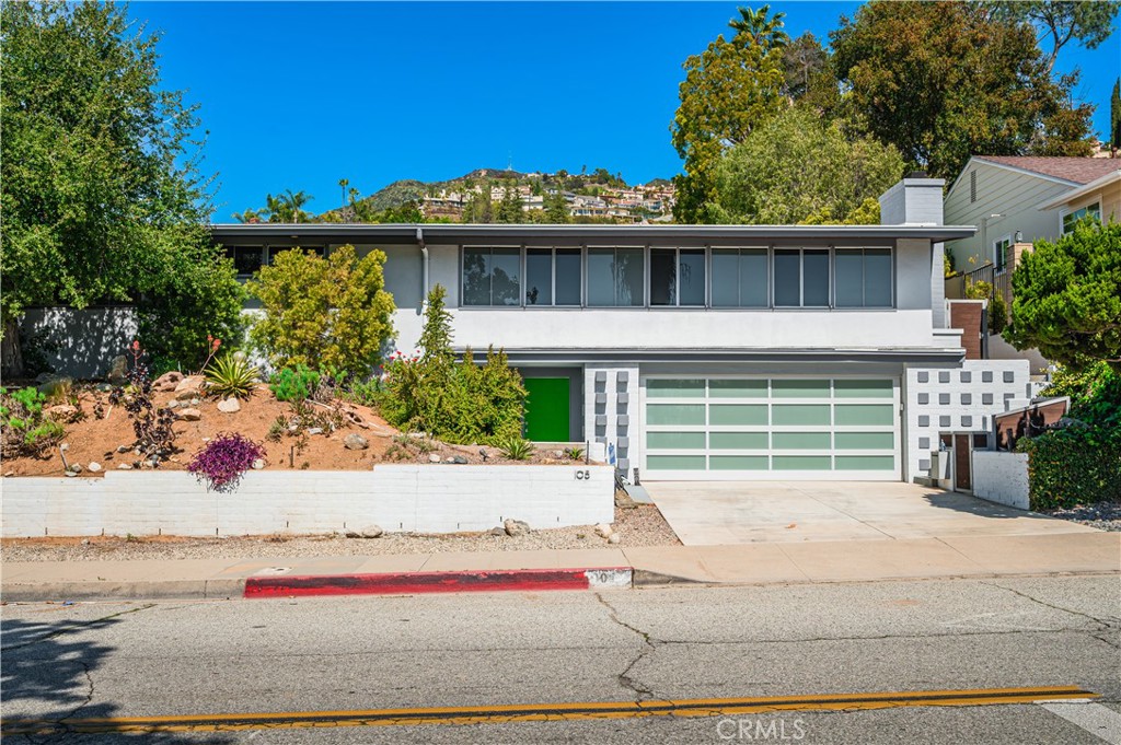 a front view of a house with a garden and mountain view