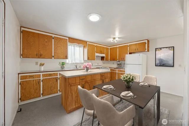 a kitchen with a refrigerator a stove a sink dishwasher with a dining table and chair