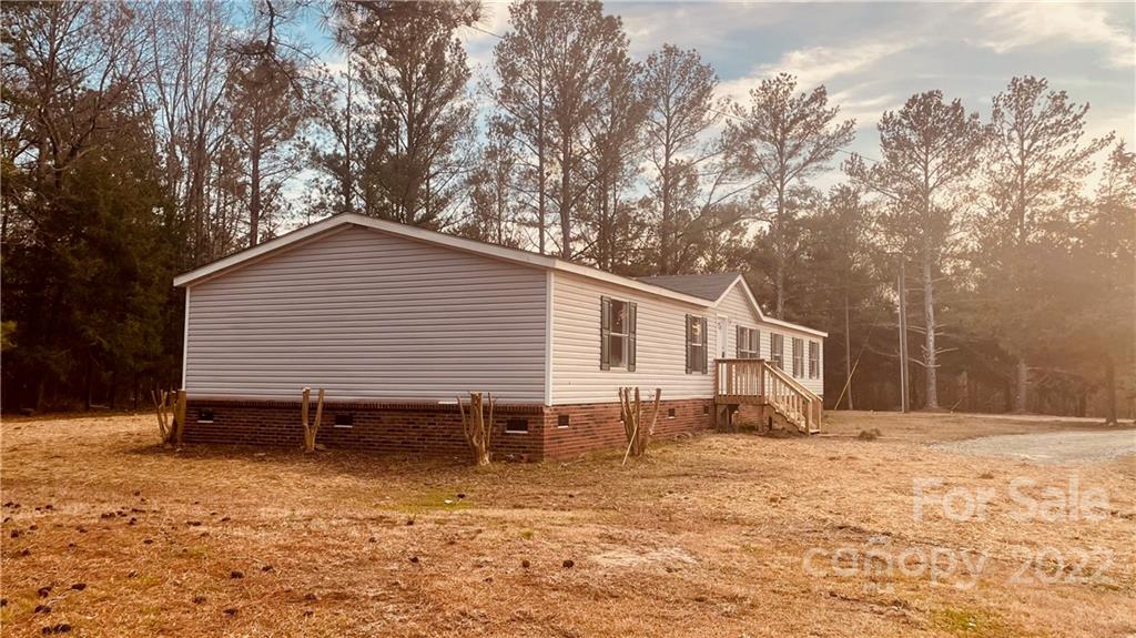 3246 Daystar Road Lancaster, SC 29720 - Photo 3 of 13 a backyard of a house with wooden deck table and chairs under an umbrella