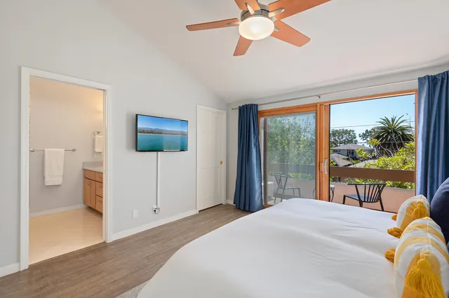 a bedroom with a bed and a large window with a flat tv screen